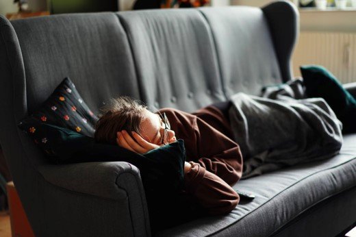 Teenager napping on a dark sofa