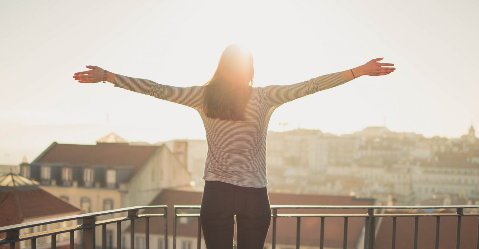 Lady arms stretched on a rooftop enjoying the sunrise