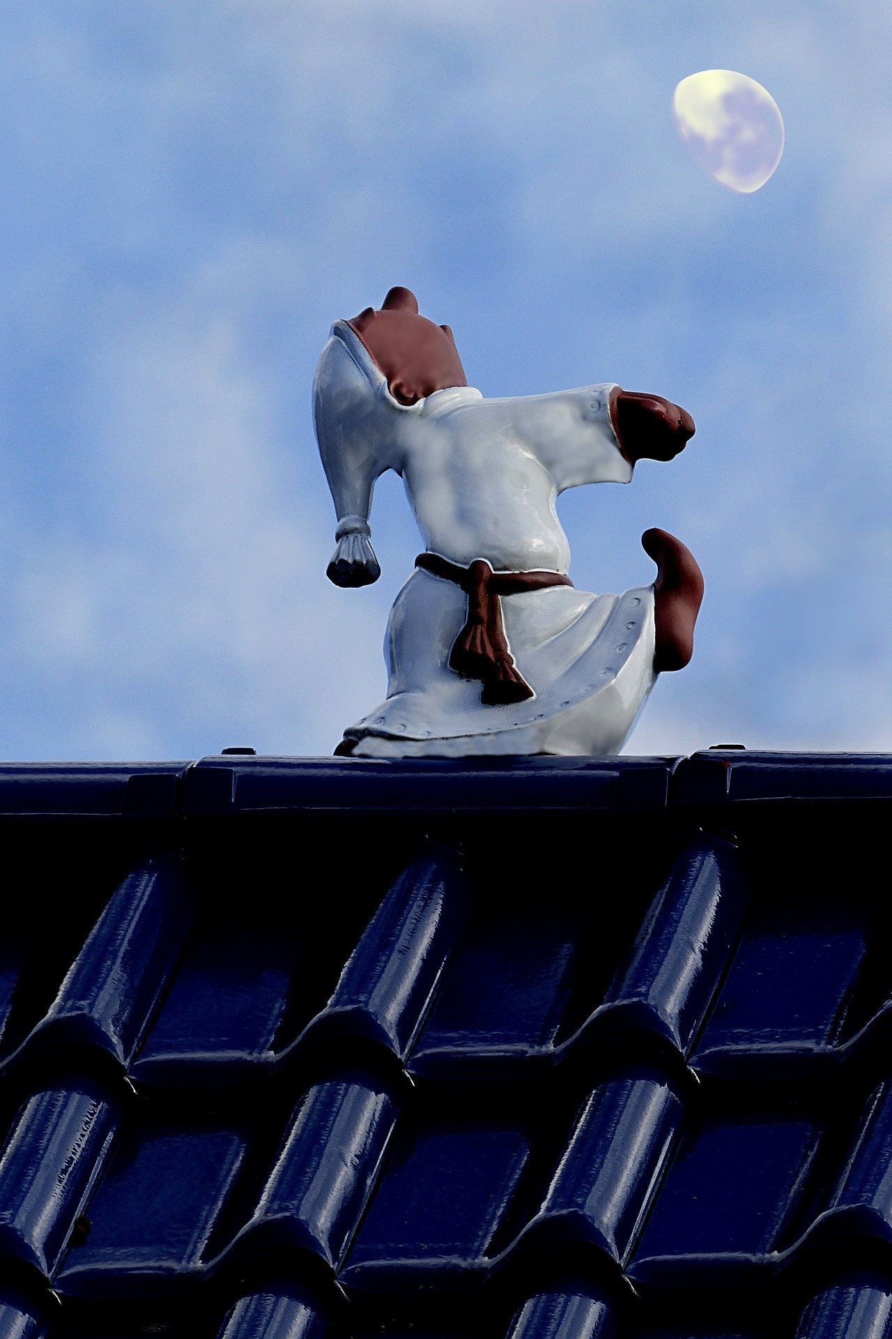 Image of a small statue of a man sleepwalking on top of a roof