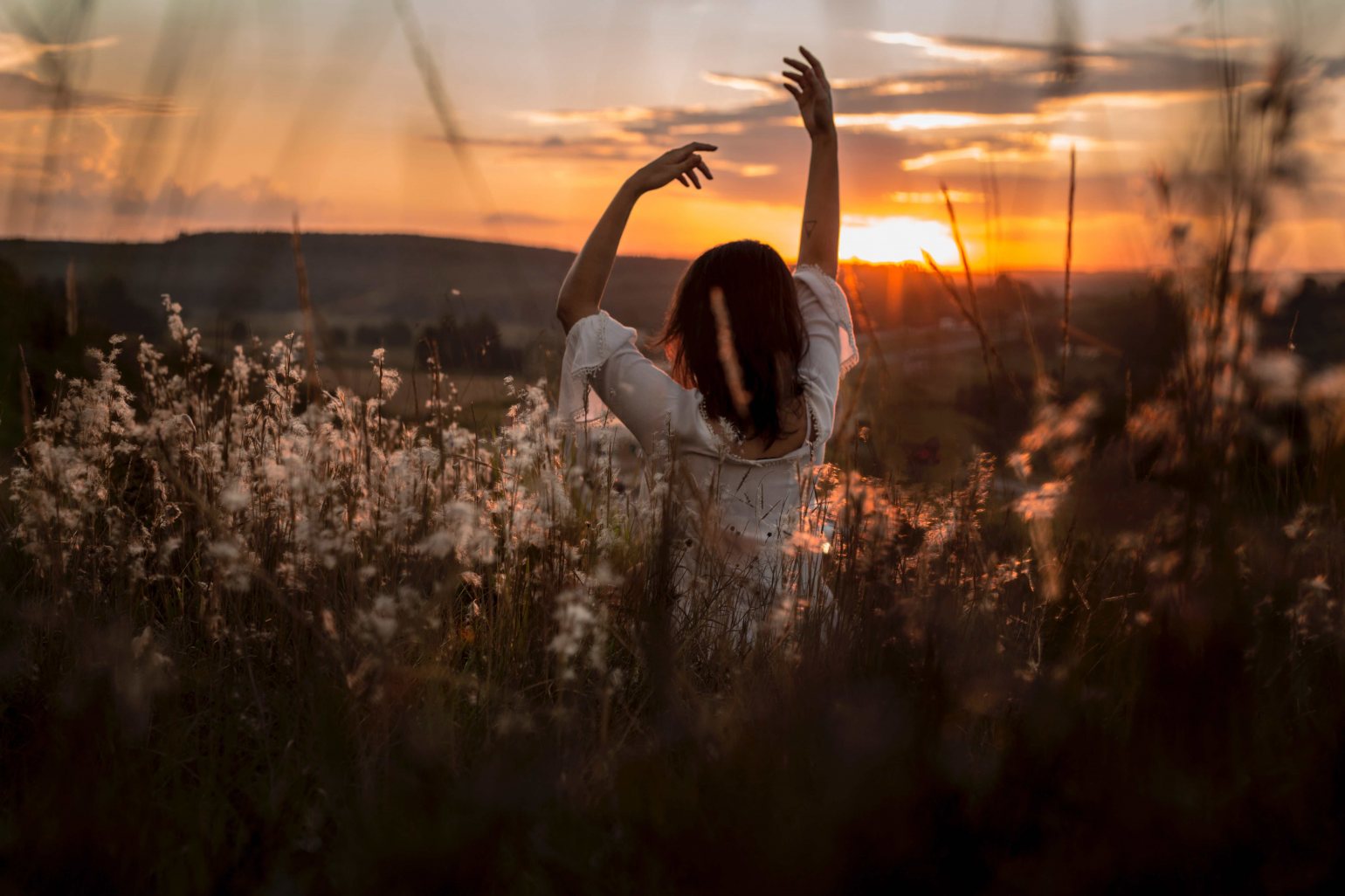 Lady arms stretched in a summer meadow enjoying the sunrise