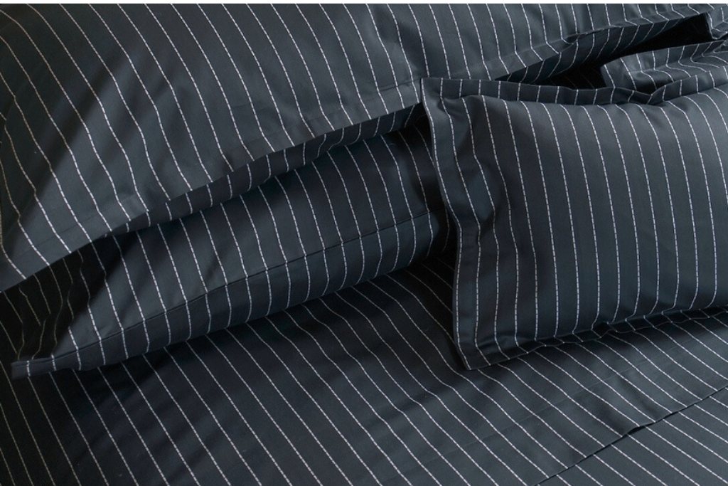 Pair of Ebony black St. Leger pinstripe cotton pillowcases neatly arranged on bed.